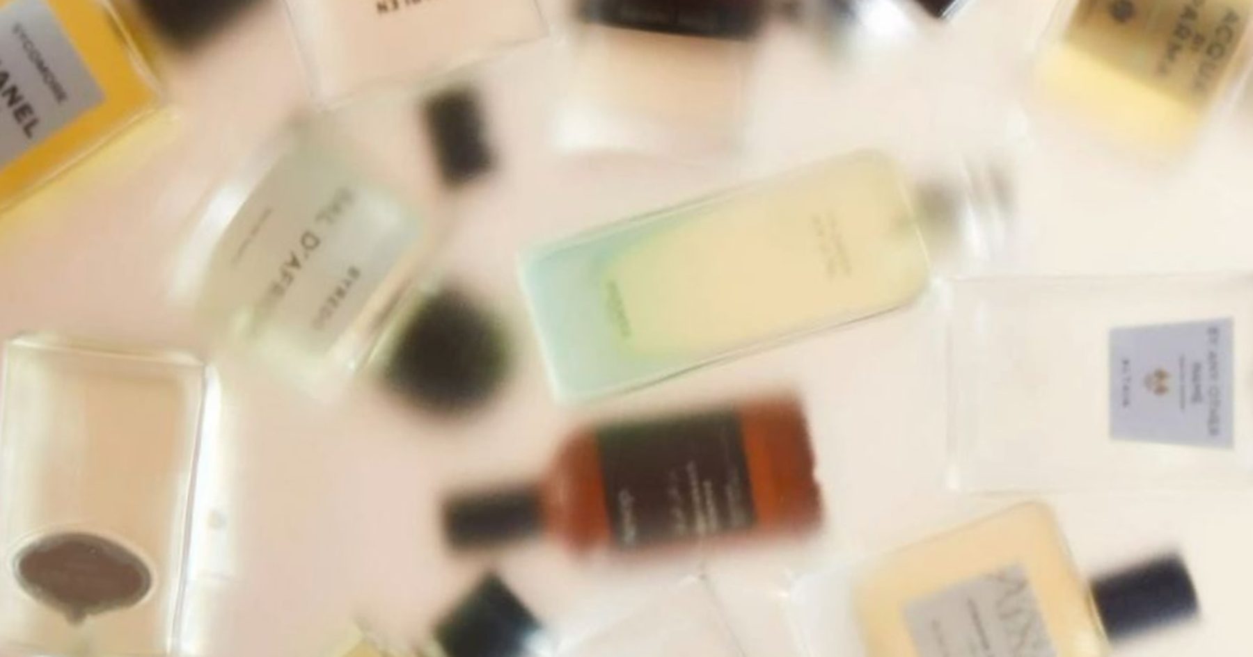 Blurred perfume bottles scattered on a pale surface